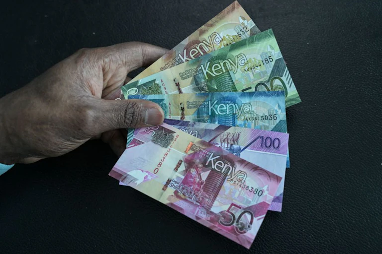 A hand holding Kenyan currency notes of 1,000, 500, 200, 100 and 50
