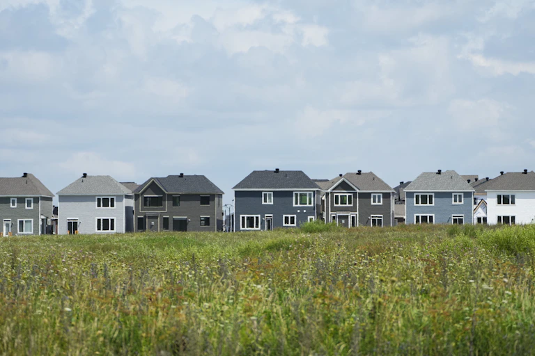 A row of detached homes in front of a field