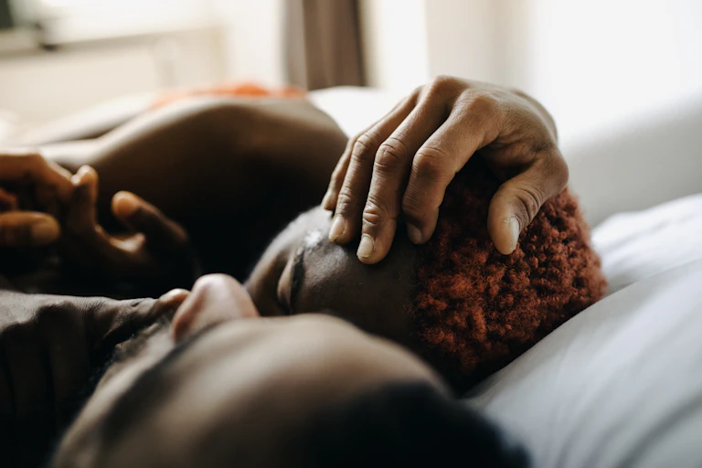 Two Black men lying together in bed
