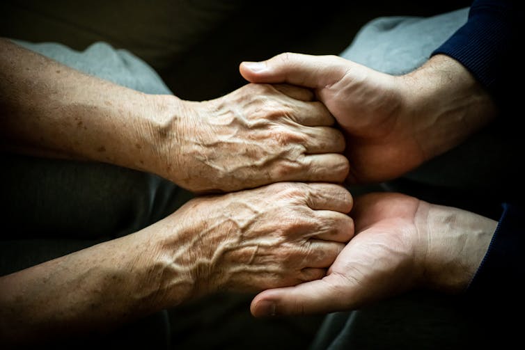 A close-up photo of two people clutching both of each other's hands.