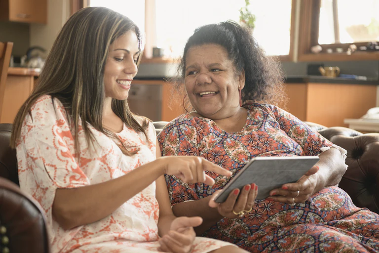 A young Aboriginal woman and an older Aboriginal women look at an iPad.