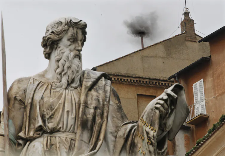 Black smoke in the background, a statue of St Paul in the foreground.