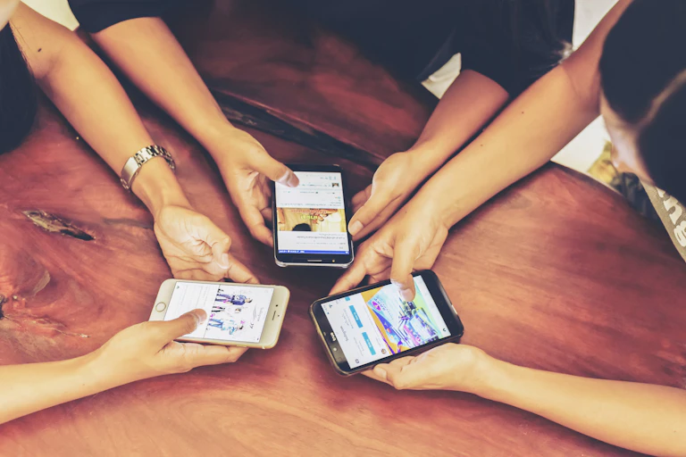 Three teens using smartphones with screens visible showing instagram.