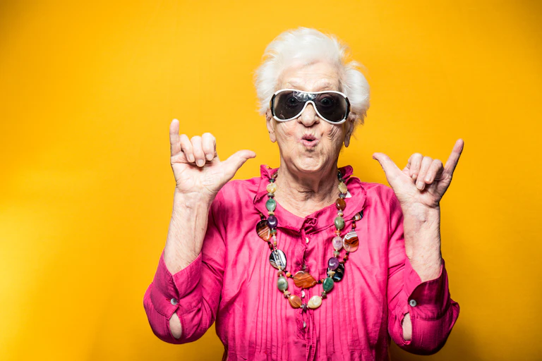 Older woman in bright clothes and sunglasses makes double shaka gesture