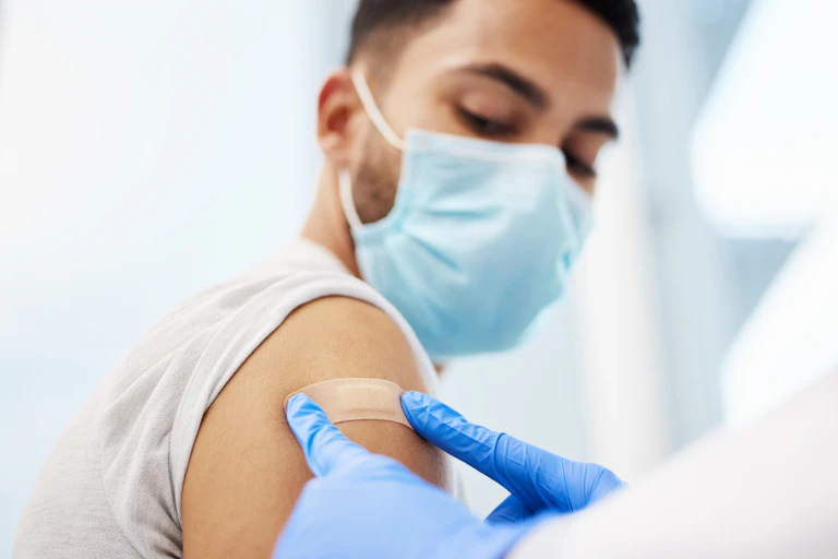 Man looks at bandaid after a vaccination