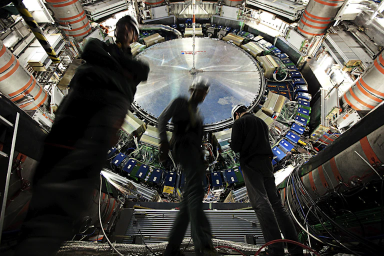 Photo of scientists in front of a large complex circular machine.