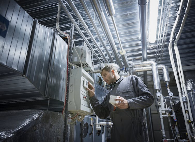 A man tends to an air handling and conditioning unit.