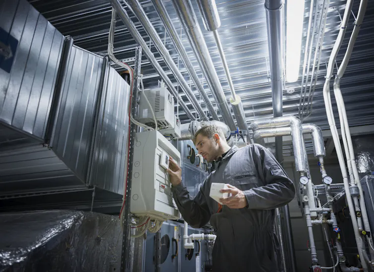 A man tends to an air handling and conditioning unit.