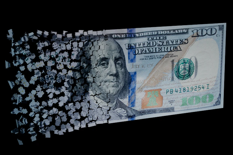 Shredded pieces of paper come together to form a U.S. $100 bill.