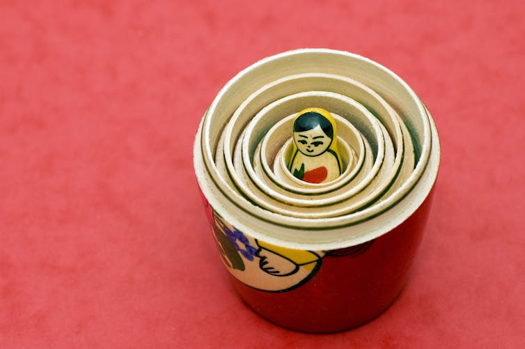 A view inside a Russian nesting doll, revealing many outer layers concealing a figure inside.