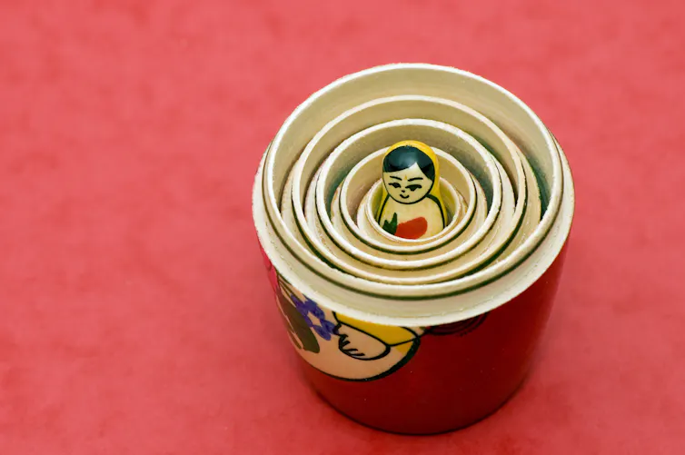 A view inside a Russian nesting doll, revealing many outer layers concealing a figure inside.