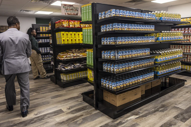 People stroll through a food pantry stocked with many matching cans and other containers.