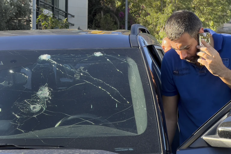 Police officer looks at a car damaged by exploding pager