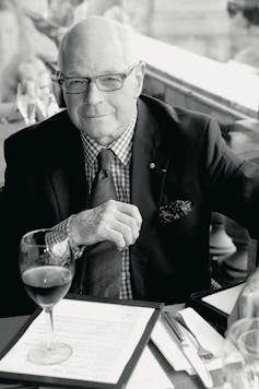 A man in glasses, suit and tie at a restaurant table