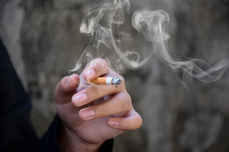 Smoke wafting from a cigarette in a woman's hand.