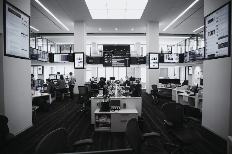 A newsroom with desks and large television screens