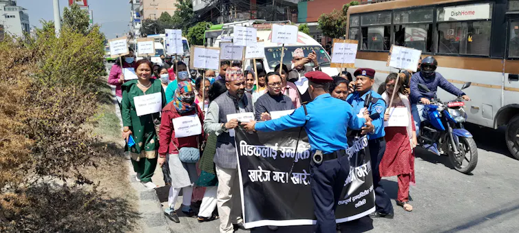A group of men and woman holding placards walk down a street