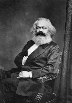 A man with a large beard sits on a chair.