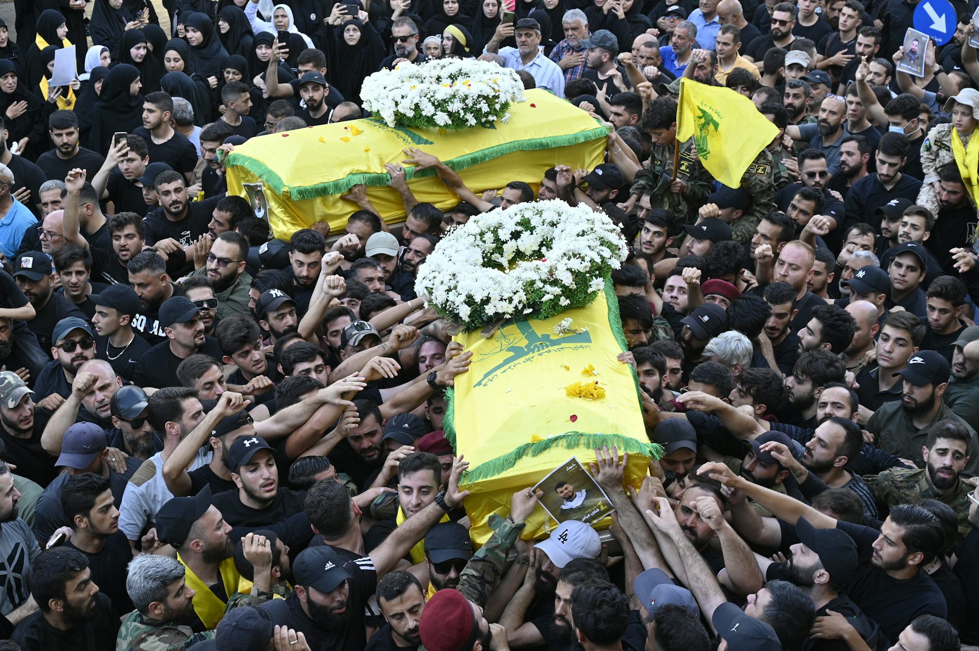 Mourners carry two coffins draped in a yellow flag.