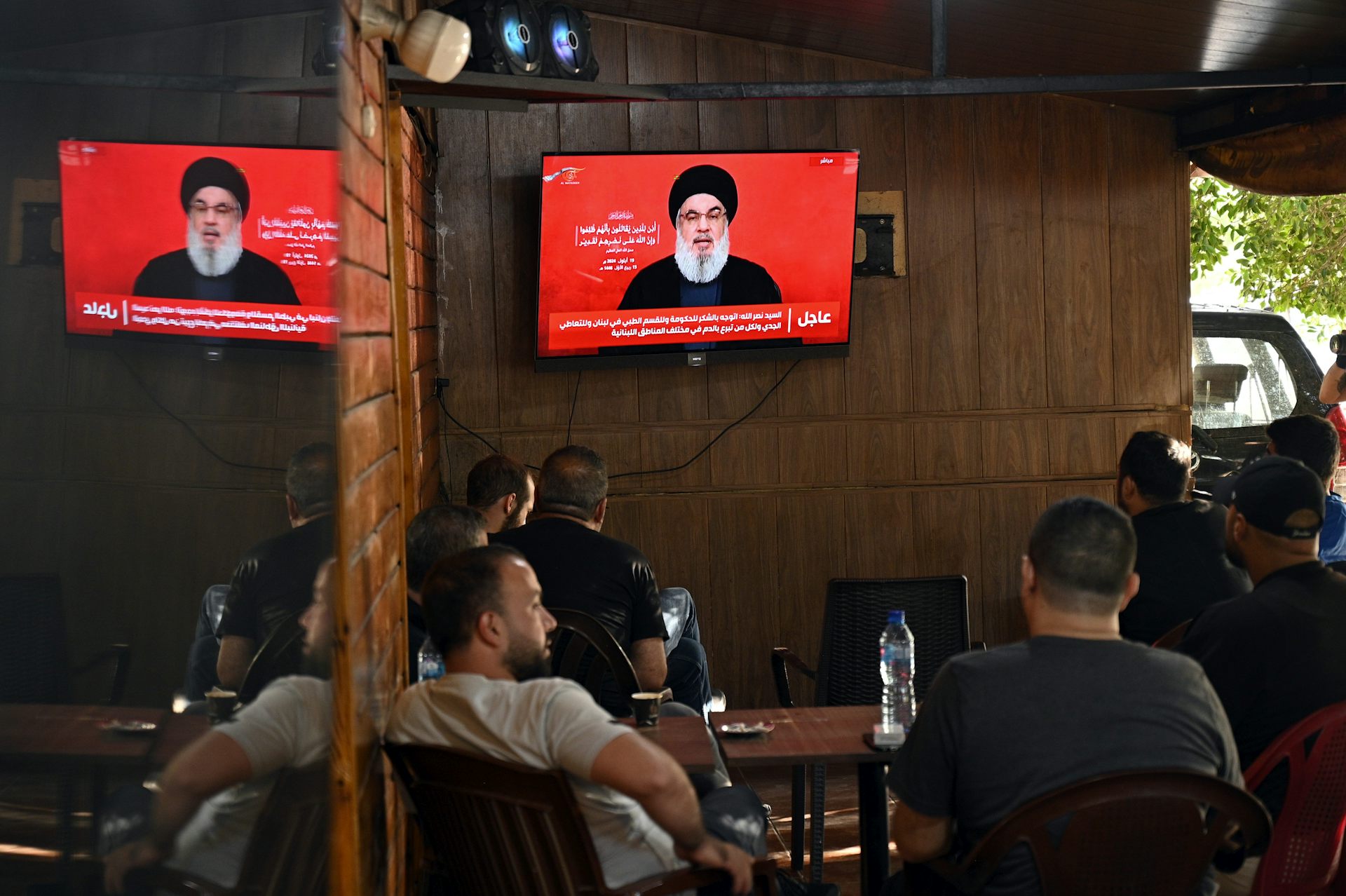 People in a coffee shop watch a televised address by Hezbollah leader Hassan Nasrallah.