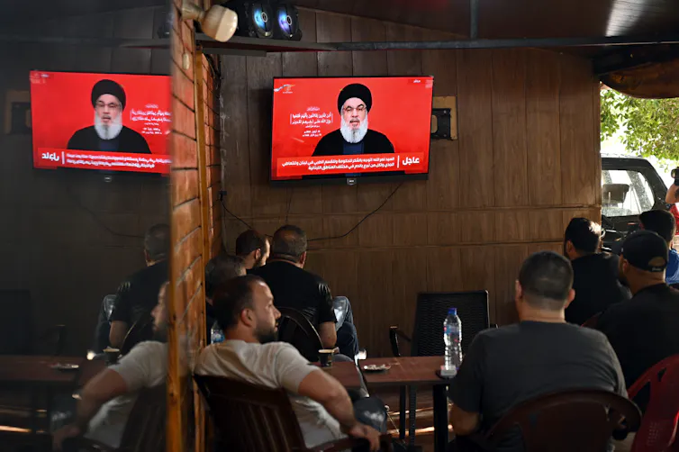 People in a coffee shop watch a televised address by Hezbollah leader Hassan Nasrallah.