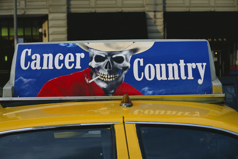 An advertisement on a taxi shows a painting of a skeleton with a cigarette in his mouth.