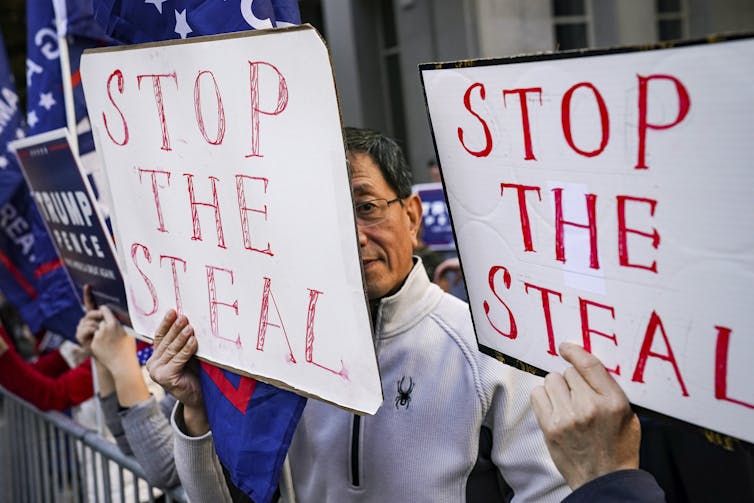 Two men carrying 'stop the steal' signs