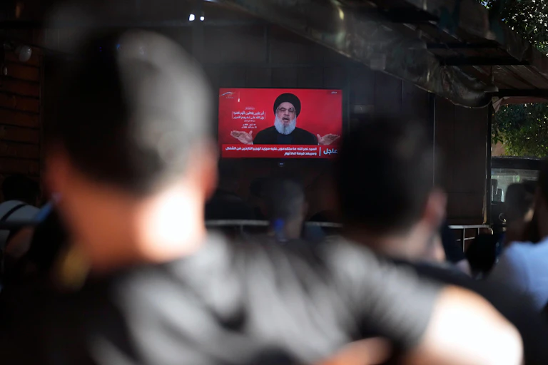 Lebanese people watch Hezbollah chief Hassan NAsralleh deliver a speech on a TV in a cafe in Beirut.