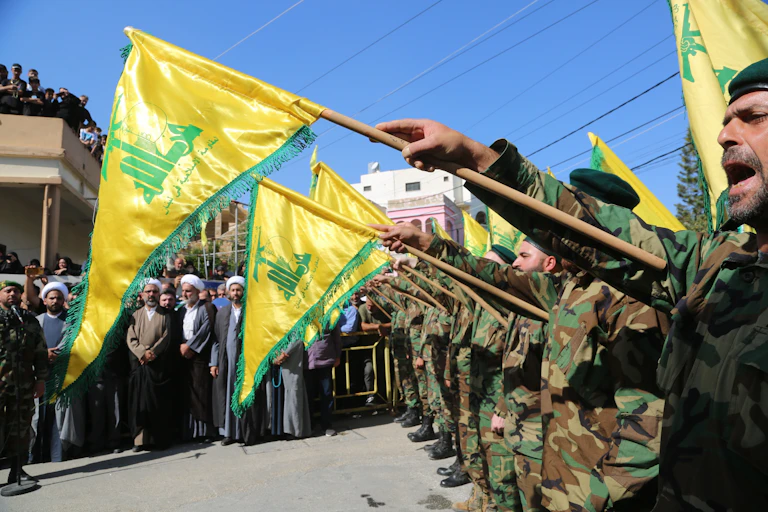 Militares sostienen la bandera de Hezbolá.