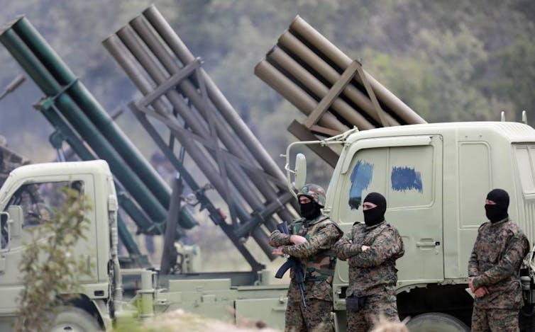 Combatientes de Hezbolá con capuchas negras frente a una camioneta.