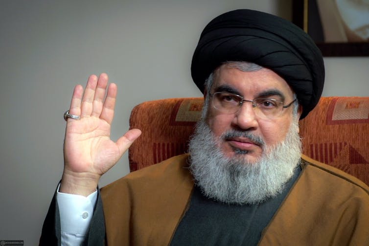 Hassan Nasrallah mira a cámara con su mano derecha levantada