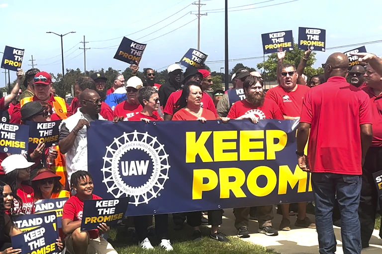 UAW members rally while holding aloft signs that say 'Keep the Promise.'