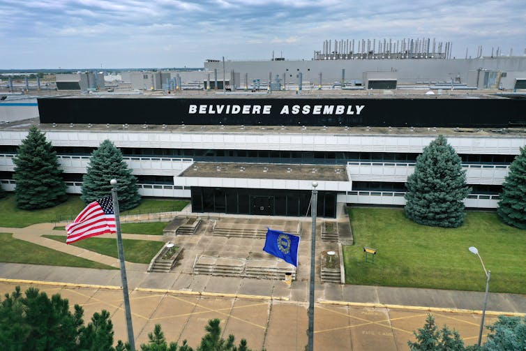 An aerial view shows and American flag flying next to a UAW flag outside an assembly plant.