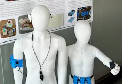 Two mannequins with devices on their bodies, with parts on the arm and ear.