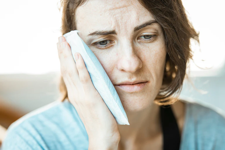 Woman in pain holds cold pack to her cheek