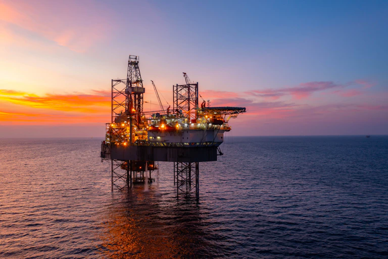Aerial view of silhouette offshore jack up drilling rig during sunset representing the oil and gas industry