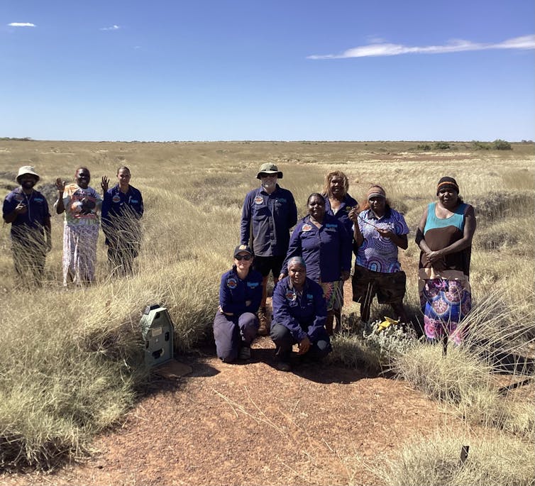 people stand in spinifex-dotted landscape