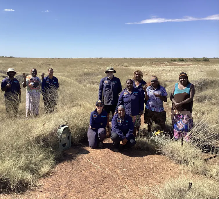 people stand in spinifex-dotted landscape