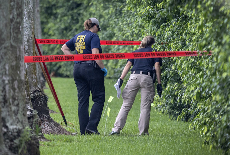 FBI officers peering into a hedge.