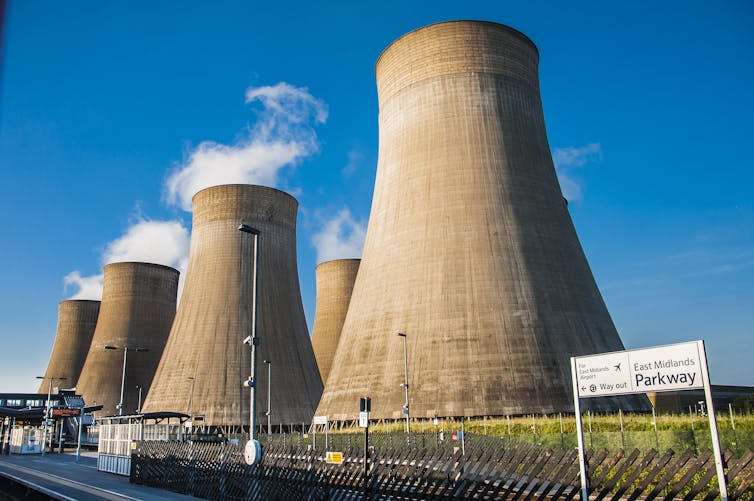Large power station cooling towers seen from nearby train station.