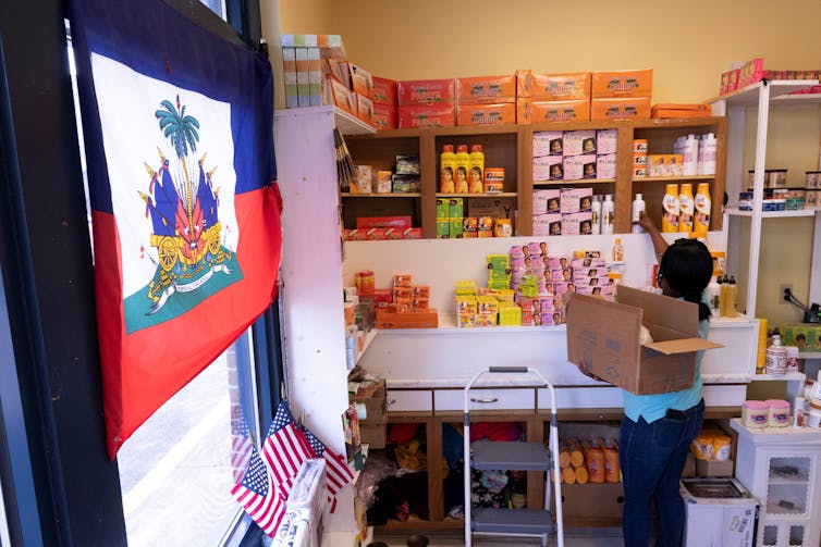 A person faces away from the camera and stacks items on a shelf in a store.