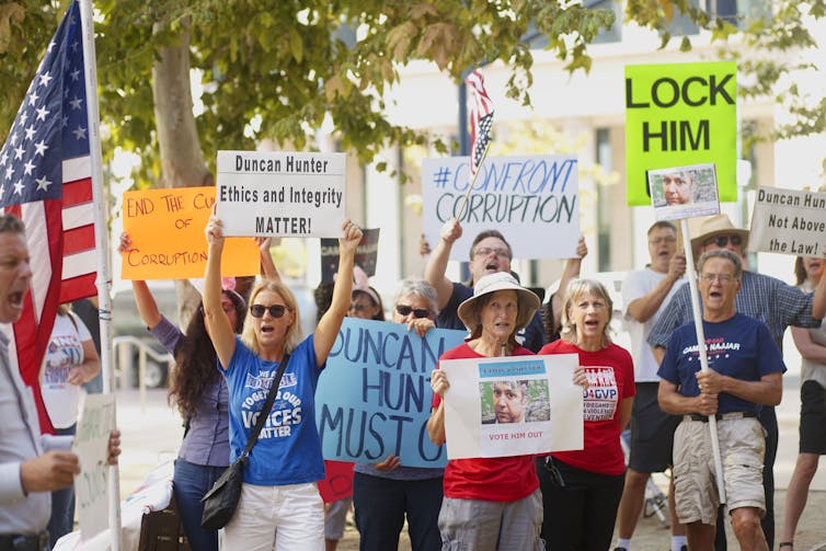 Protesters hold signs reading 'lock him up' and 'Duncan Hunter must go.'