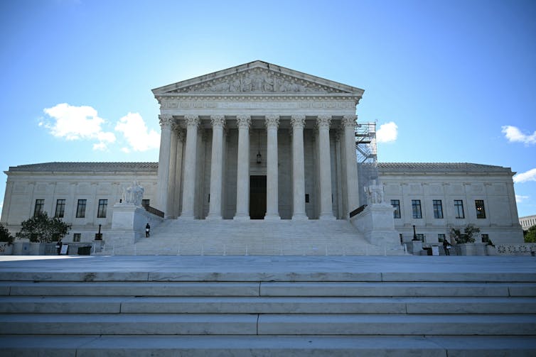 A large white building with a columned middle section at the top of wide marble steps.