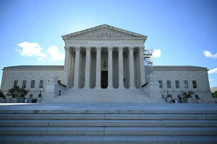 A large white building with a columned middle section at the top of wide marble steps.