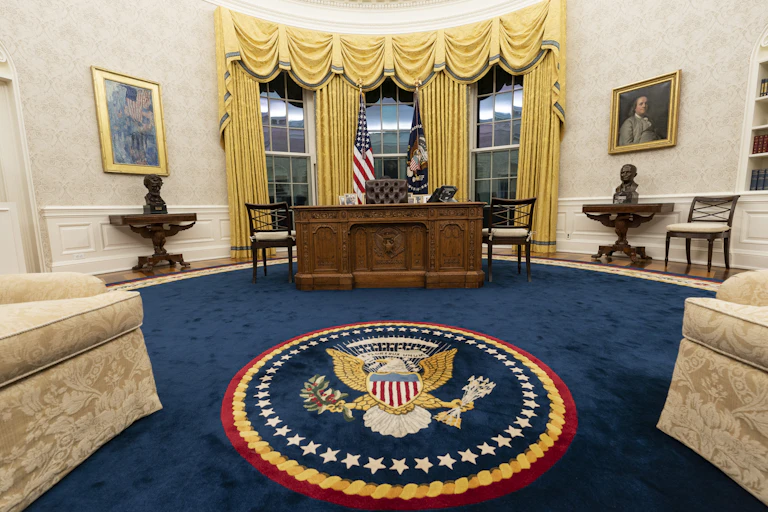 An oval office with fancy furnishings and paintings.