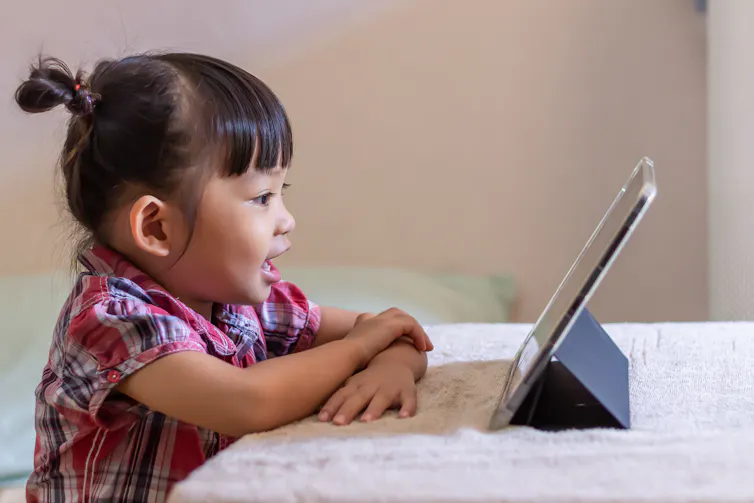 A small child in profile looking at a tablet