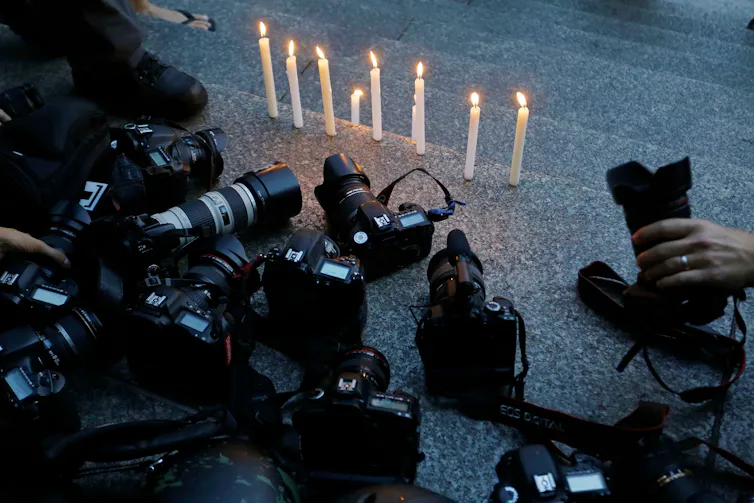 Para jurnalis foto di Rio De Janeiro menyalakan lilin saat mengheningkan cipta setelah seorang jurnalis video terbunuh saat meliput unjuk rasa di sana.