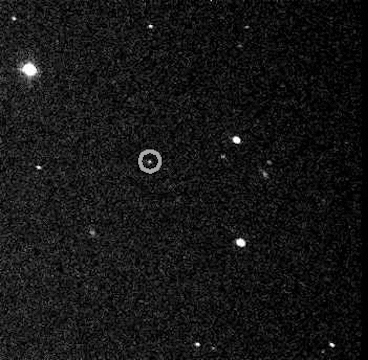 A gif of the sky where there are a few stars that are stationary. One small dot (J002E3) is moving across the image.