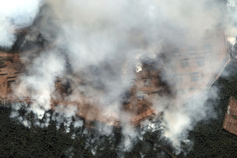 A satellite image shows smoke rising from an ammunition depot.