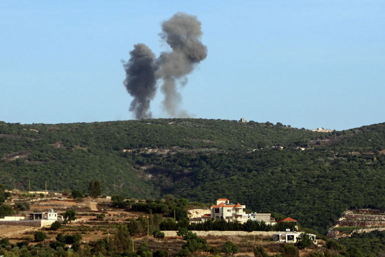 A plume of black smoke rises from a hill.
